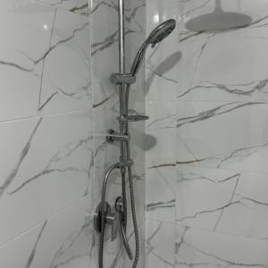 מקלחת עם ראשי מקלחת וכיורים על קיר שיש