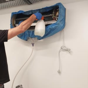 אדם מנקה מזגן עם בקבוק ספריי