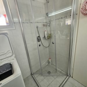 מקלחון זכוכית עם בקבוקי שמפו וסבון