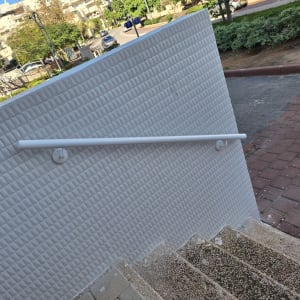 מעקה לבן על קיר מרוצף ליד מדרגות חיצוניות