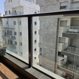 מעקה זכוכית במרפסת עם נוף לבניינים