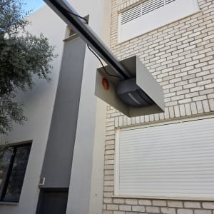 מנוע שער חשמלי מותקן על קיר לבנים ליד חלון