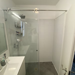 מקלחון זכוכית עם כיור ומראה בחדר אמבטיה מודרני