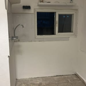 קיר לבן עם חלון וברז, ללא אנשים או טקסט.