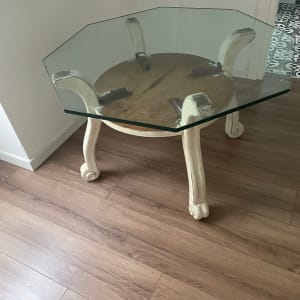 שולחן זכוכית עם רגליים מעוצבות על רצפת עץ