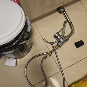 ברז וכבלים על רצפה ליד פח אשפה