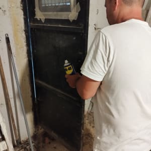 אדם מתקן דלת עם תרסיס WD-40 ליד מטאטא