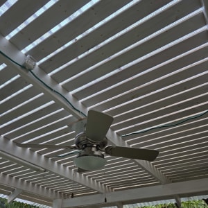 מאוורר תקרה מותקן על פרגולה עם חיווט חשמלי גלוי.