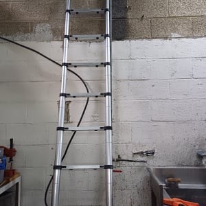 סולם מתכת ליד כיור עם מברשת וכלי עבודה
