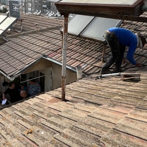 אדם עובד על גג רעפים עם כלים