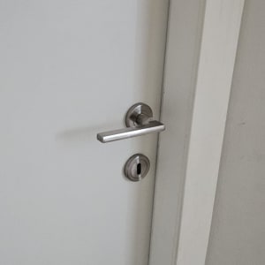 ידית דלת כסופה עם מנעול על דלת לבנה