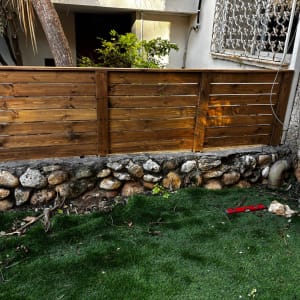גדר עץ עם אבנים ודשא סינתטי