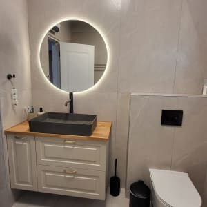 חדר אמבטיה משופץ עם כיור, מראה עגולה ותאורה מודרנית