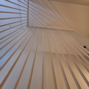 קורות מתכת צבועות בלבן עם צללים על הקיר