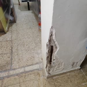 קיר עם טיח מתקלף וחשיפת ברזל בניין