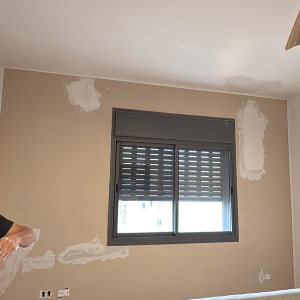 אדם מכין קיר לצביעה עם שפכטל וחומר מילוי