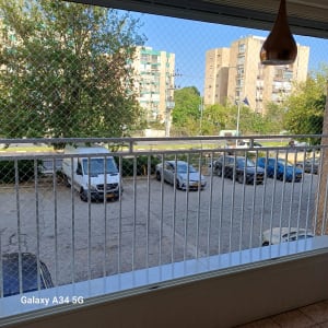 רשת הגנה על מרפסת עם נוף לבניינים ועצים