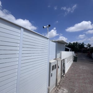מצלמת אבטחה מותקנת על עמוד ליד גדר לבנה