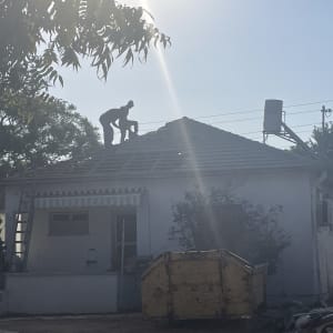 אדם עובד על גג בית עם סולם ומיכל מים