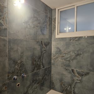 קיר אמבטיה עם אריחים חדשים וברזים מותקנים