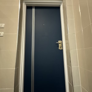 דלת כחולה עם ידית כסופה ופסים לבנים