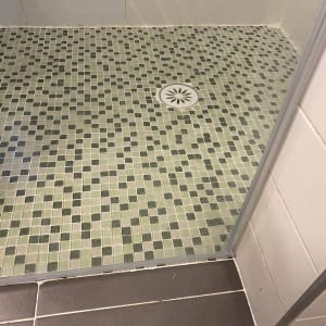 רצפת מקלחת עם אריחים ירוקים וניקוז עגול