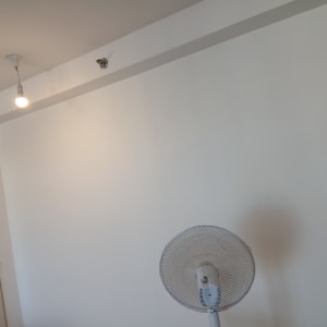 קיר פנימי צבוע בלבן ומאוורר עמוד בחדר