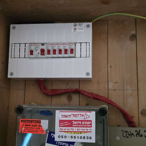 לוח חשמל עם מפסקים אדומים מותקנים על קיר עץ