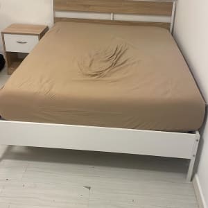 מיטה עם מצעים חומים ליד שידה בחדר שינה