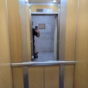 מראה במעלית עם השתקפות של אדם מחזיק טלפון