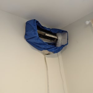 מזגן מכוסה בכיסוי כחול על קיר לבן