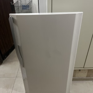 דלת מקרר מונחת על רצפה ליד ארון
