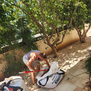 אדם עובד בגינה עם עצים ושקי גינון
