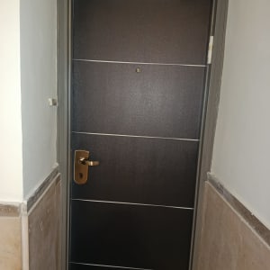 דלת חומה עם ידית זהב במסגרת אפורה