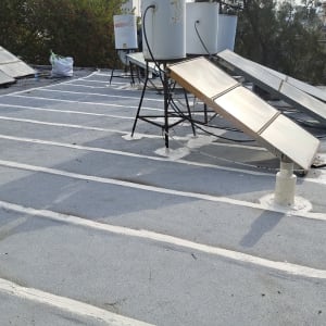 קווים לבנים של איטום על גג שטוח עם קולטי שמש