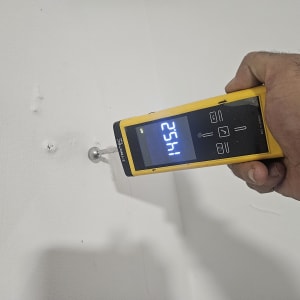 מד לחות על קיר לבן עם יד אוחזת