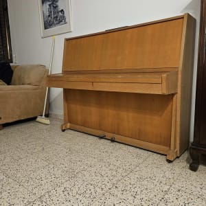 פסנתר עץ עומד על רצפת אריחים ליד מטאטא