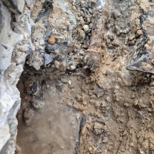 צינור חלוד עם נזילה באדמה רטובה