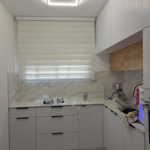 וילון גלילה במטבח מודרני עם ארונות לבנים ותאורה מעוצבת