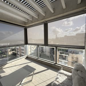 מרפסת עם סוככים נגללים ונוף עירוני