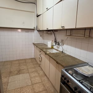 מטבח עם ארונות לבנים, כיור וברז, תנור גז