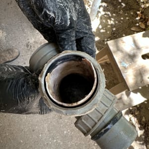 ידיים בכפפות מחזיקות צינור אינסטלציה ישן ומלוכלך