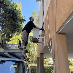 אדם מתקין מזגן על קיר חיצוני של בניין