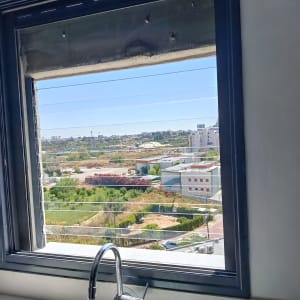חלון אלומיניום עם נוף חיצוני וברז מטבח
