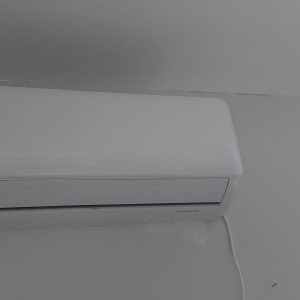 מזגן קיר לבן מותקן על קיר עם וילון לידו