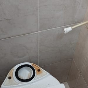 כלי עבודה של אינסטלטור על אסלה, כולל מפתח צינורות וסרט איטום