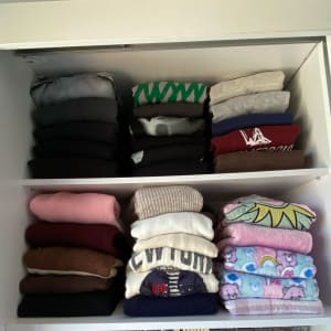 בגדים מקופלים בארון על מדפים מסודרים