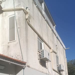 אדם עומד ליד בניין עם מזגנים על הקיר