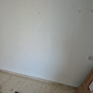 קיר עם חורים וכלי עבודה על הרצפה