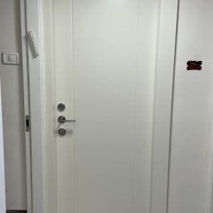 דלת לבנה עם ידית מתכת וכפתורי נעילה